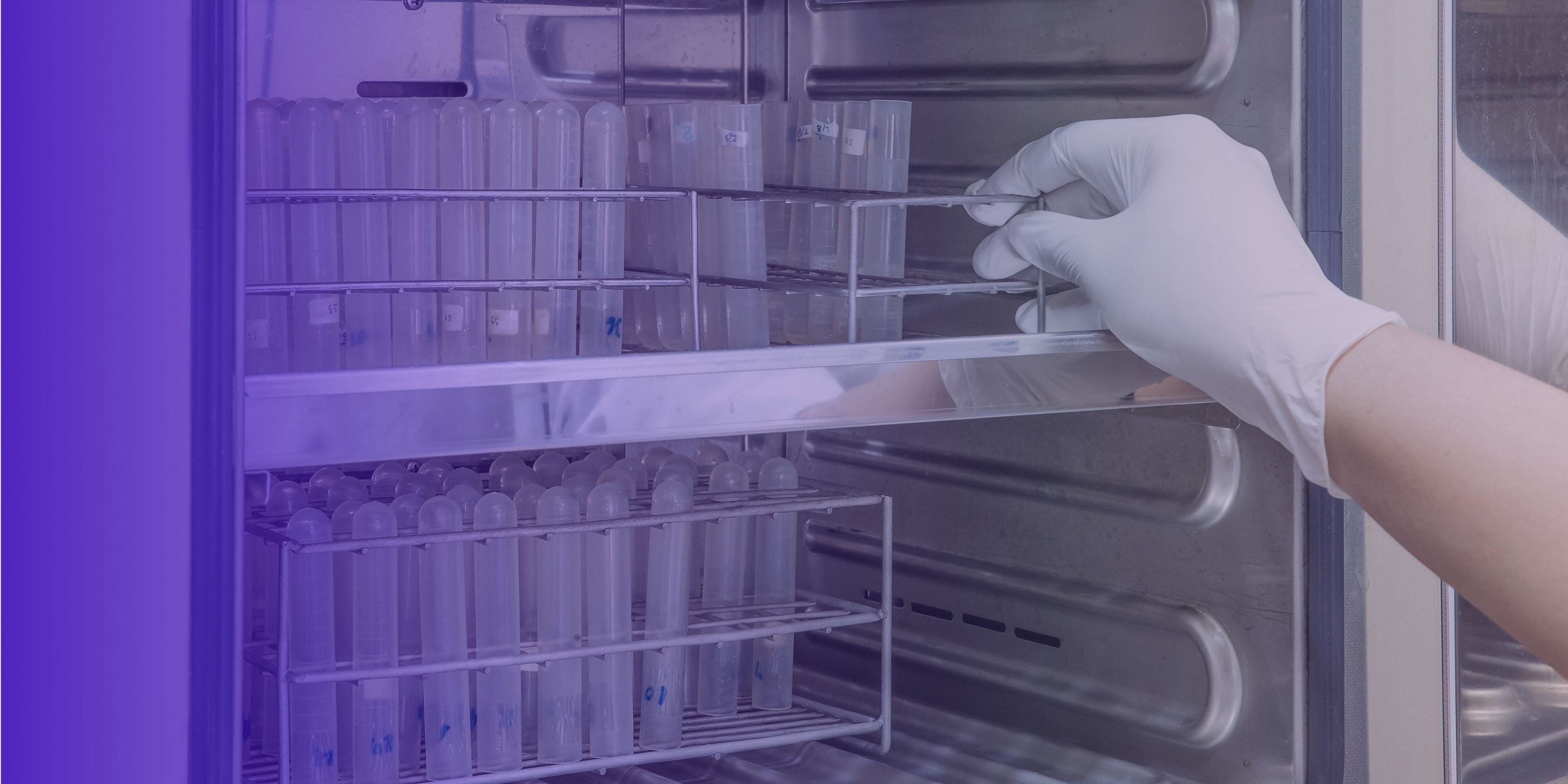 Gloved hand handling test tubes in a metallic laboratory